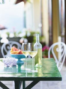 calici e bottiglia di vino al sole