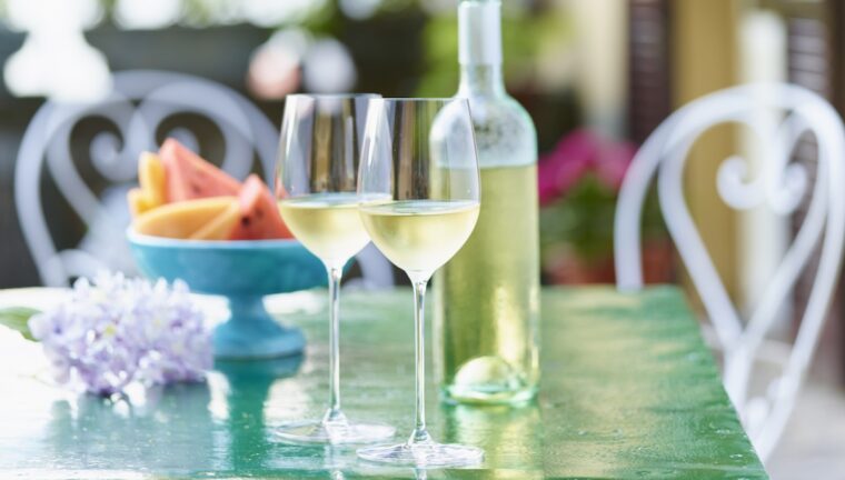 calici e bottiglia di vino al sole