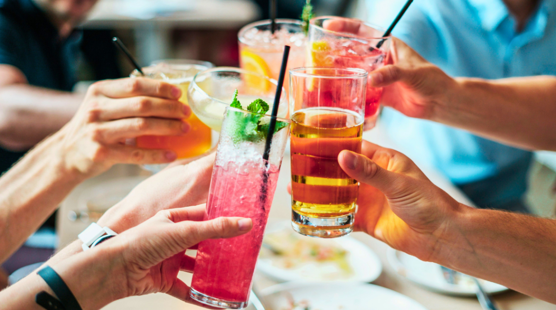 Diverse mani brindano con dei cocktail a basso contenuto alcolico durante l'aperitivo