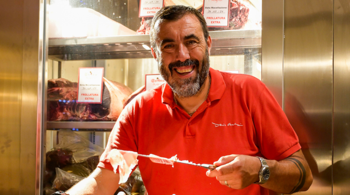 Il patròn Omar Barsacchi tiene in mano un coltello con delle fette di prosciutto crudo appena tagliate