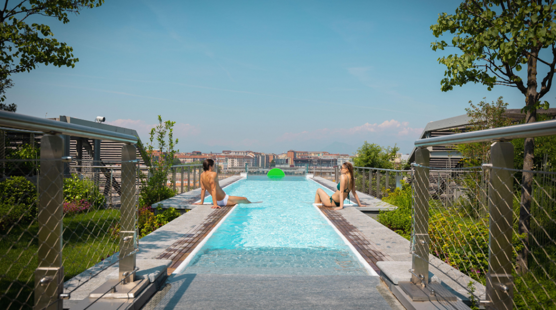 Rooftop con piscina a sfiori di Otium, Torino. Sul terrazzo, a bordo piscina, sono sedute due persone