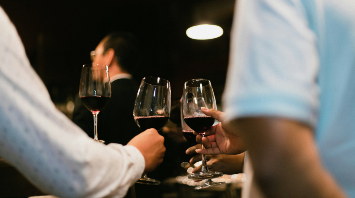 Persone brindano con un calice di vino rosso