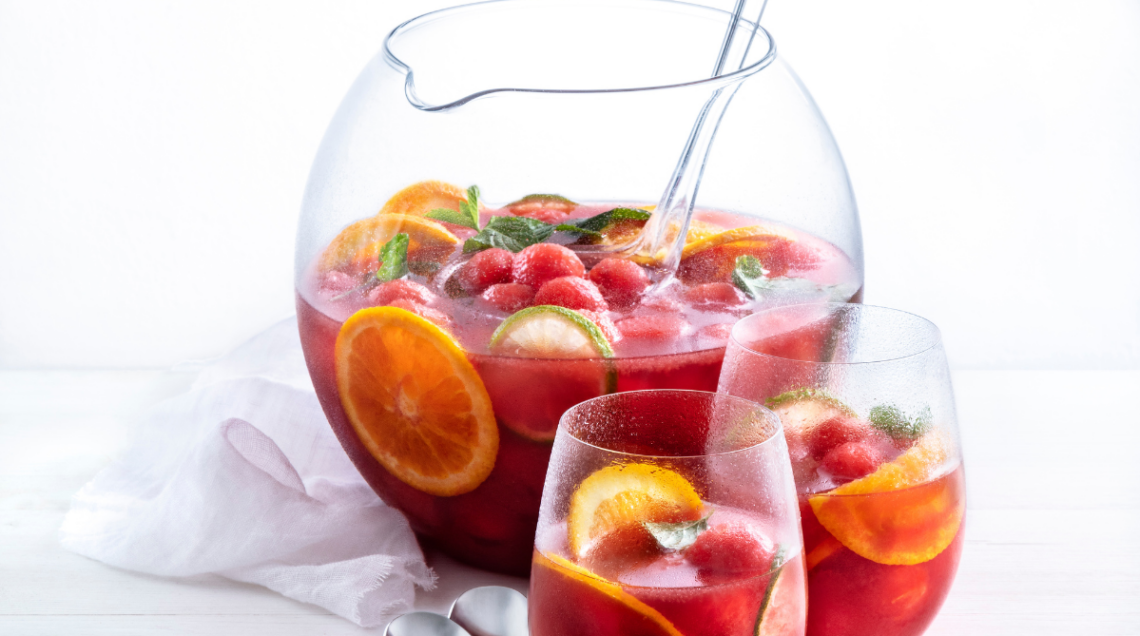 Una brocca ampia e circolare e due bicchieri di vetro, tutti riempiti di sangria