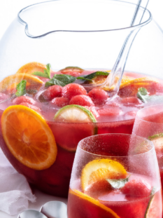 Una brocca ampia e circolare e due bicchieri di vetro, tutti riempiti di sangria