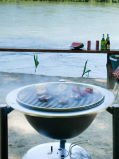 Di fronte a uno specchio d'acqua c'è una griglia rovente sopra la quale stanno cuocendo carne e verdure, delle sedie e dei tavolini. Tutto pronto per la grigliata estiva