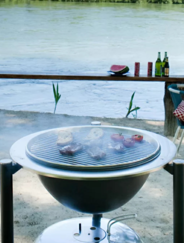 Di fronte a uno specchio d'acqua c'è una griglia rovente sopra la quale stanno cuocendo carne e verdure, delle sedie e dei tavolini. Tutto pronto per la grigliata estiva