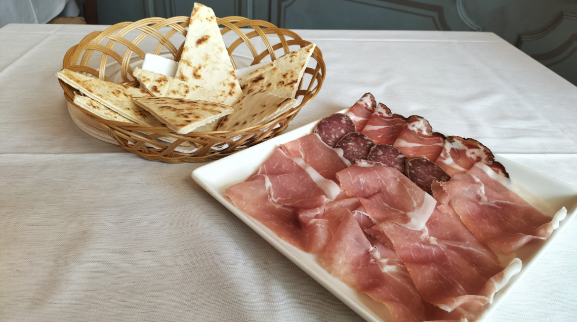 la piadina della Trattoria il Passatore tagliata a spicchi con un piatto di salumi