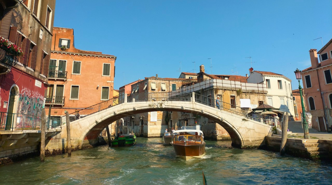 Un ponte di venezia sotto il quale stanno navigando delle imbarcazioni