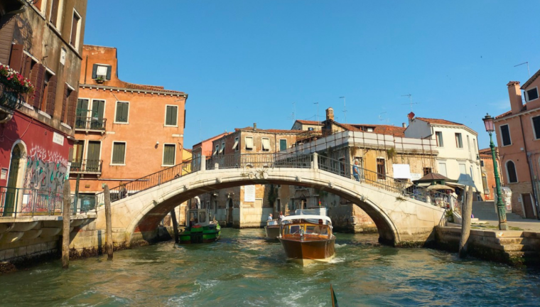Un ponte di venezia sotto il quale stanno navigando delle imbarcazioni