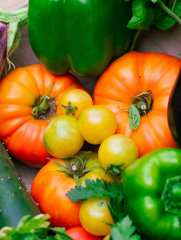 pomodori rossi, pomodori gialli, cetrioli, peperoni, melanzane, basilico in una ciotola di legno