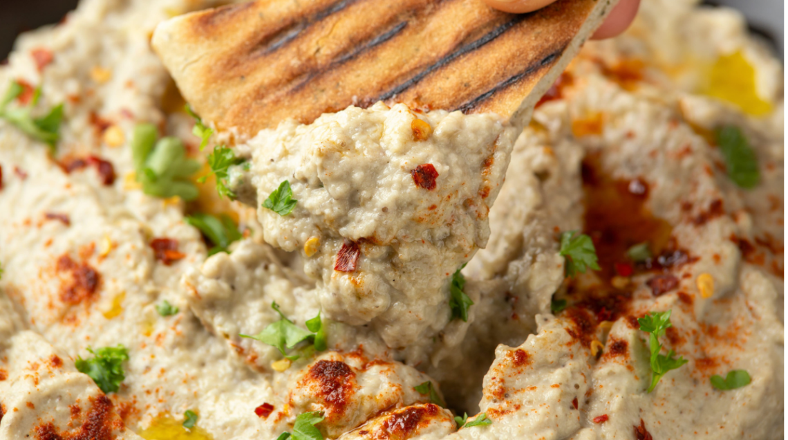 Baba ganoush (crema di melanzane mediorientale), condita con foglioline di prezzemolo e sommacco