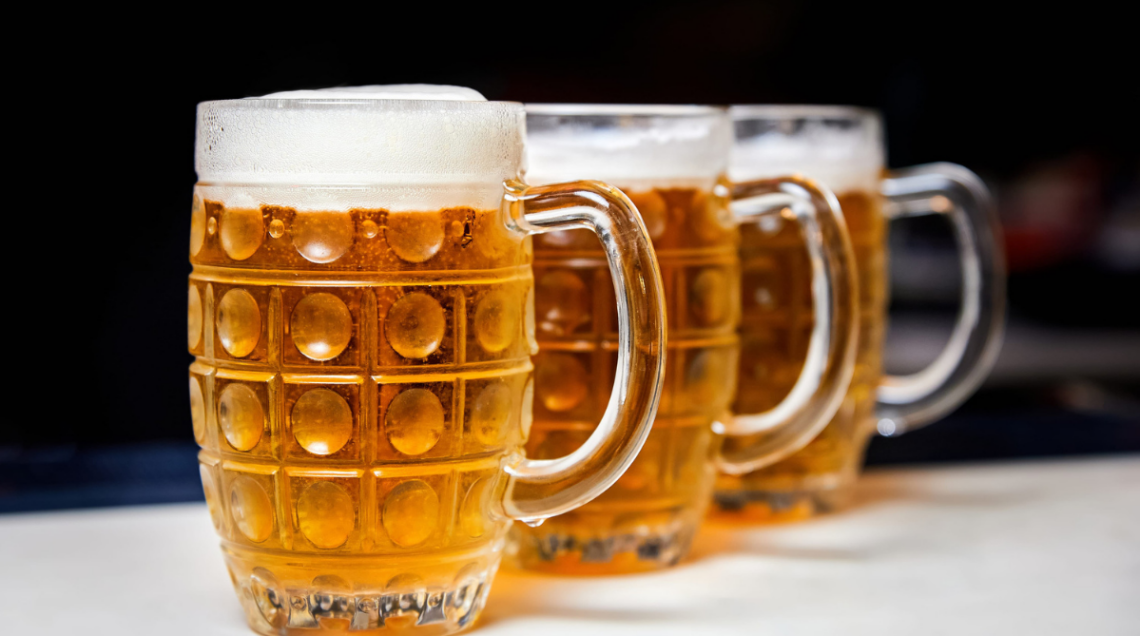 Grandi boccali di vetro colmi di birra chiara, fredda, con tanta schiuma
