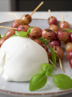 piatto di burrata con spiedini di uva grigliata e basilco