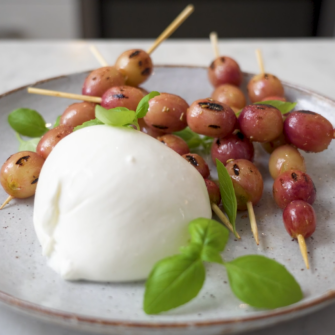 piatto di burrata con spiedini di uva grigliata e basilco