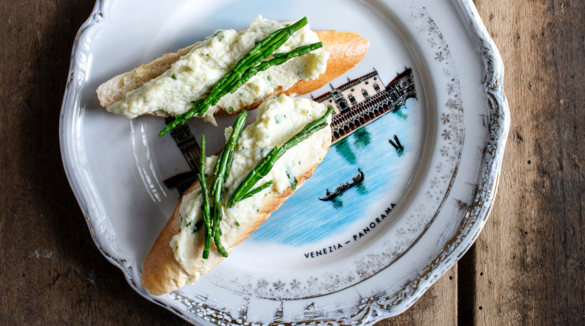Baccalà mantecato con la salicornia su un piatto decorato con i canali di venezia