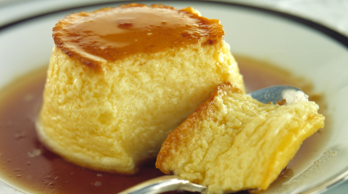 Crème caramel in un piatto con un cucchiaino e un pezzo staccato