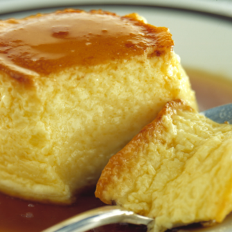 Crème caramel in un piatto con un cucchiaino e un pezzo staccato