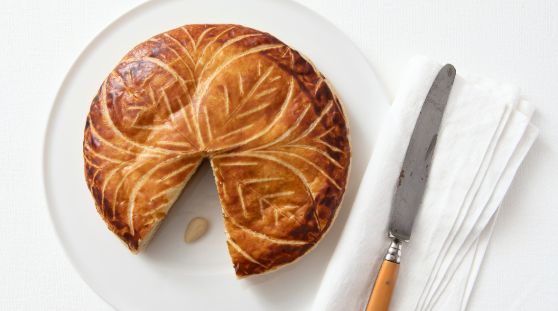 Galette des rois su base bianca con coltello e tovagliolo bianco