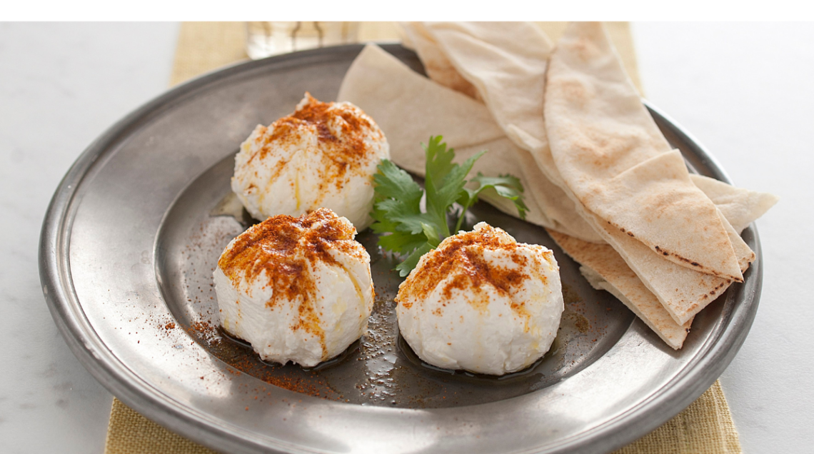 Un piatto con il formaggio di yogurt levantino chiamato labneh, tre piccole porzioni spolverizzate con paprika e servite con pane pita