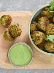 Polpette di verdure con chutney alle erbe su un vassoio di legno con piccola ciotola di salsa verde a lato