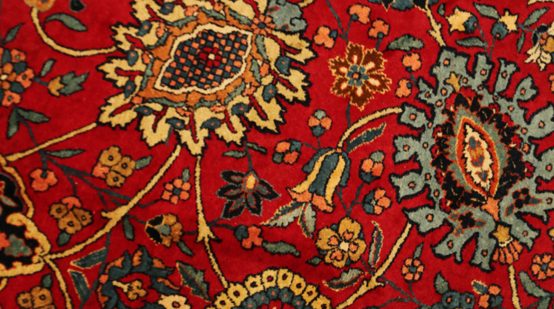 Particolare del disegno a fiori di un tappeto persiano a fondo rosso