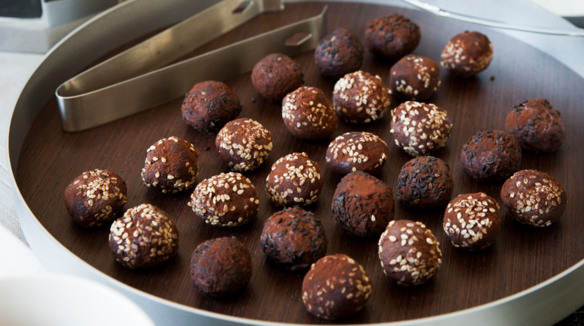 tartufi di cioccolato al sesamo serviti su un vassoio elegante e rotondo, con pinza per il servizio