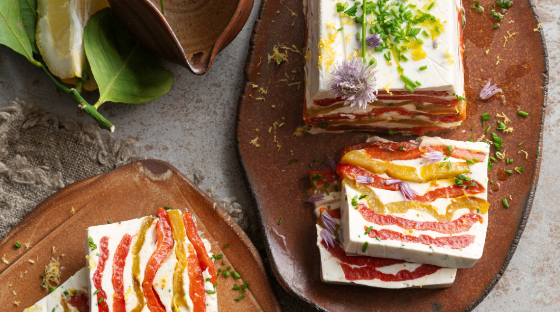 Terrina di robiola e peperoni tagliata a fette su un tagliere di legno