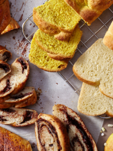 Trecce dolci e pan brioche tagliate a fette e disposte su un piano grigio