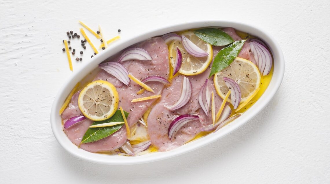 fettine di vitello marinate con fette di limone, foglie di alloro e cipolla rossa