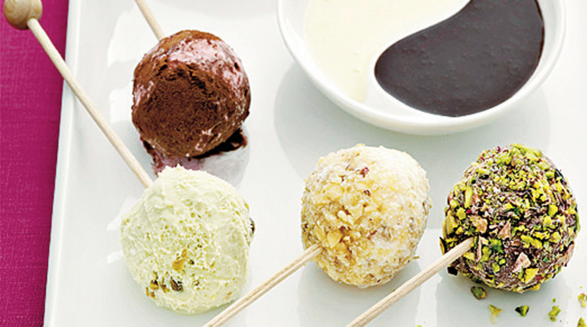 praline di gelato su stecchini ricoperte di salse al cioccolato e granelle assortite