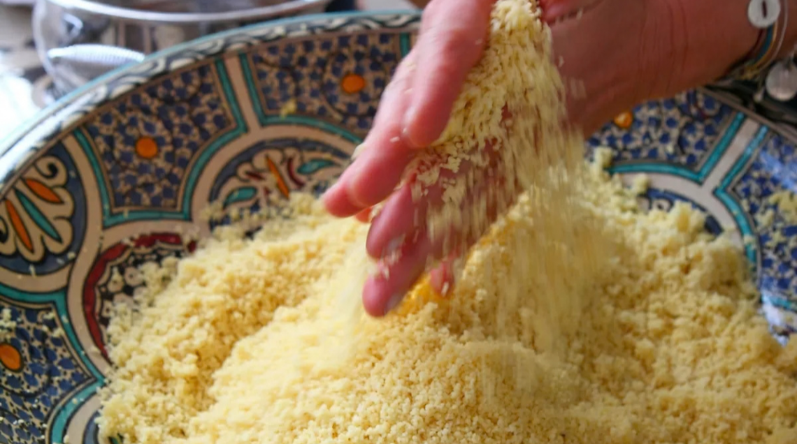 Due mani sgranano il cous cous in una ciotola etnica