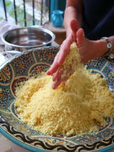 Due mani sgranano il cous cous in una ciotola etnica