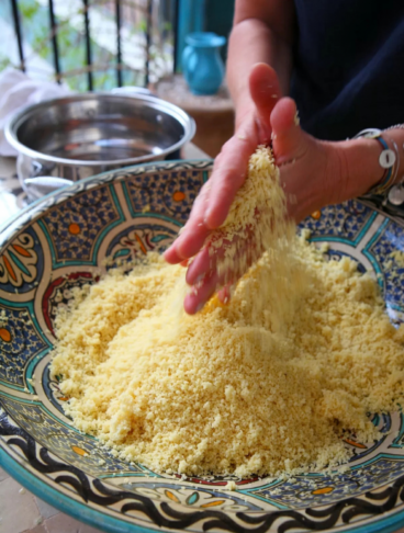 Due mani sgranano il cous cous in una ciotola etnica