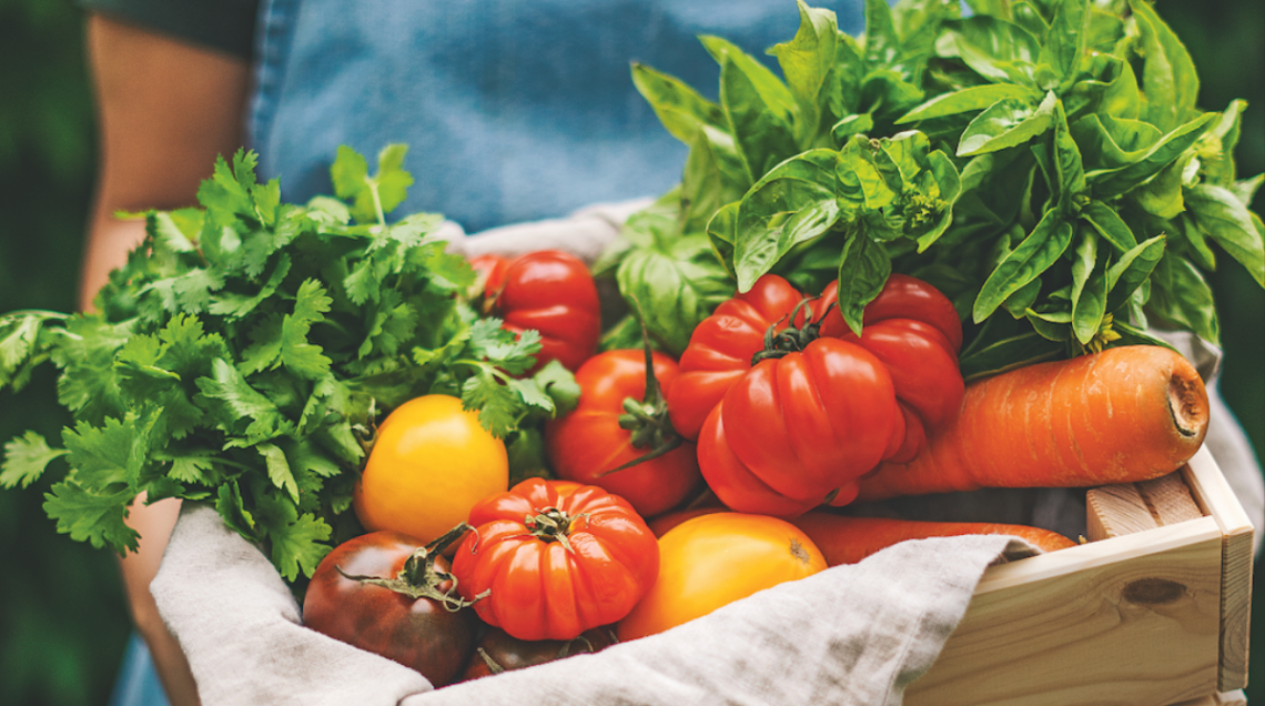 Cassetta di legno con pomodori, carote, basilico e altre verdure