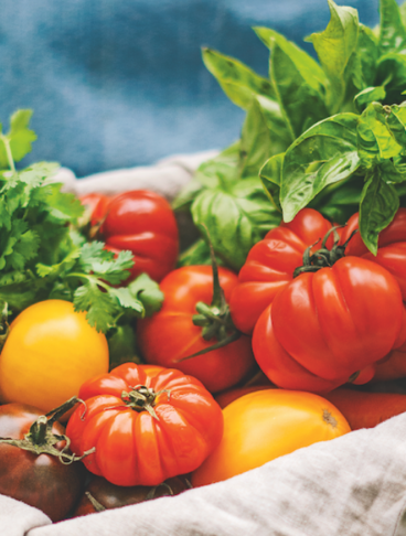 Cassetta di legno con pomodori, carote, basilico e altre verdure