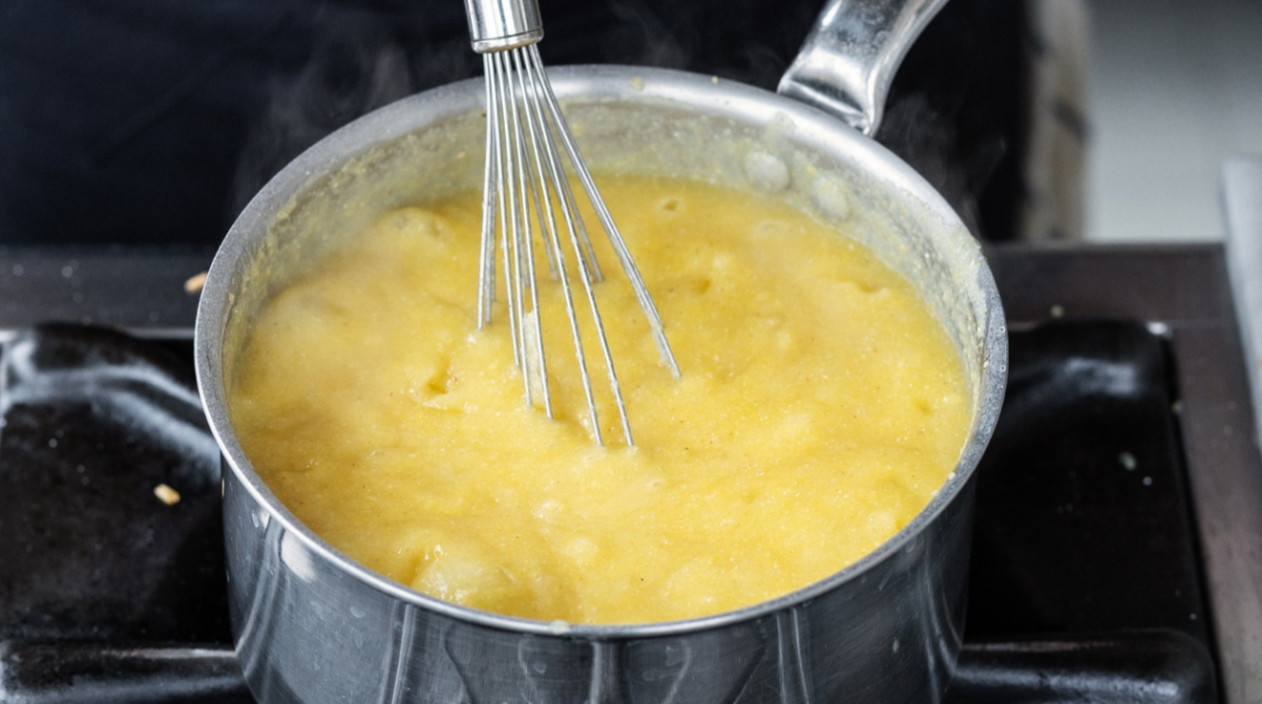 polenta che viene rimescolata in una pentola con una frusta