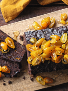 Torta al cioccolato con sopra kumquat con una fetta tagliata e fiocco di neve ritagliato di carta
