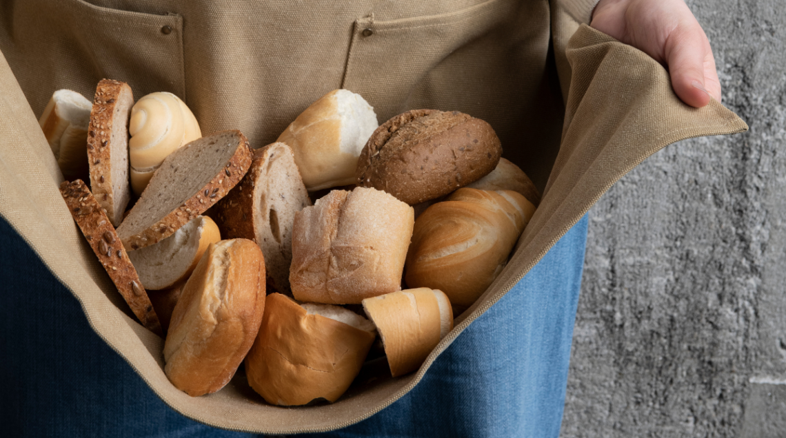 Una persona tiene diversi tipi di pane nel suo grembiule da cucina