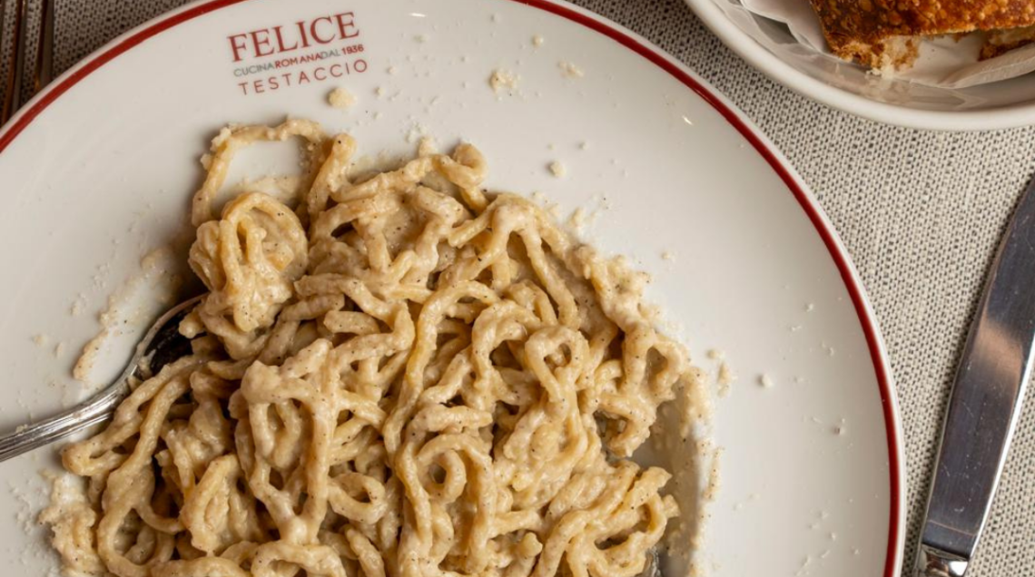 cacio e pepe servita su un piatto fondo bianco con bordo rosso, marchiato Felice a Testaccio